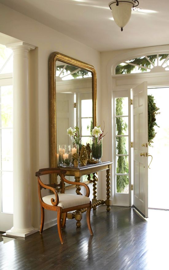 An oversized gilded mirror establishes a beautiful display in this foyer - Tradi...