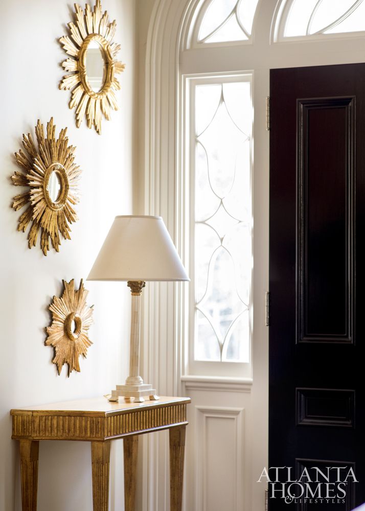 In the living room, a trio of sunburst mirrors from English Accents reflect the ...