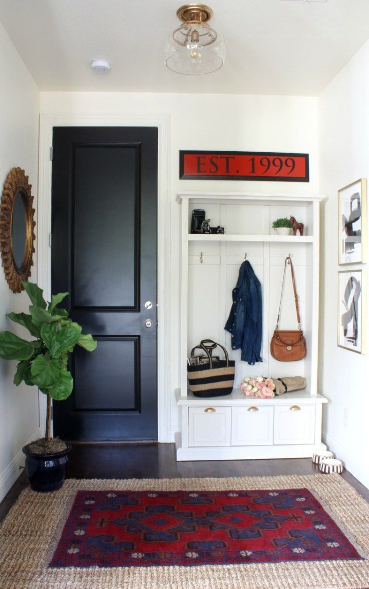 Simple mudroom makeover with layered rugs, a storage locker and black doors to h...