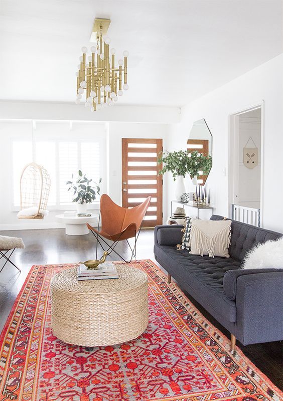 Modern bohemian inspired living room with a large rug, gray sofa, and a chandeli...