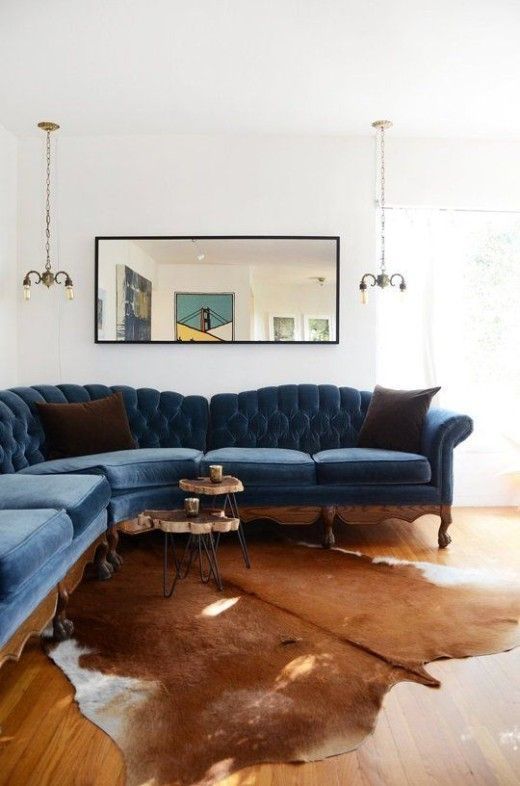 We're swooning over this blue tufted velvet sofa and cowhide rug combination...