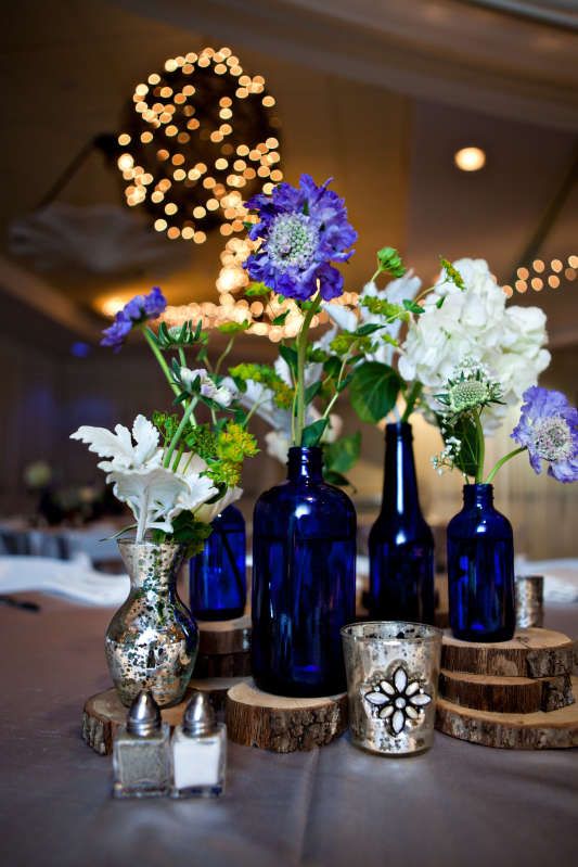 Cobalt blue bottles, silver mercury glass, and wood rounds with blue and white s...