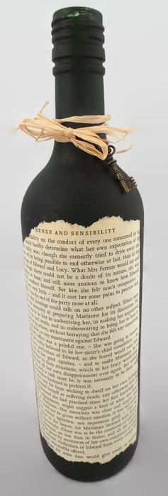 A standard glass Wine bottle hand painted in Black.  Decorated with an aged book...