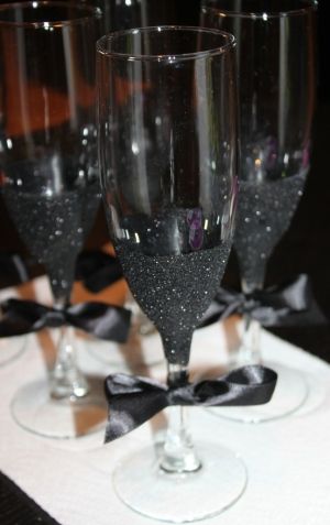 DIY Black Glitter Champagne Flutes. Use glue, paint brush, black glitter, and a...