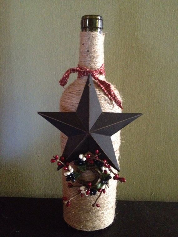 Wine bottle wrapped in jute twine with a metal star and some small decorations. ...