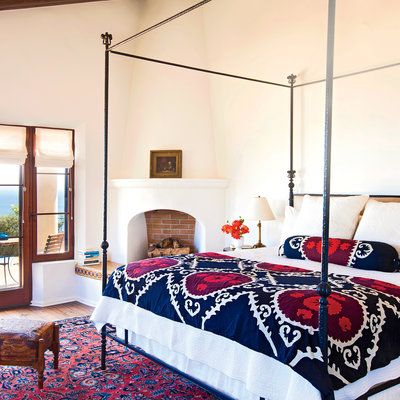 A richly colored rug and a vibrant suzani pattern on the bed's quilt and bol...
