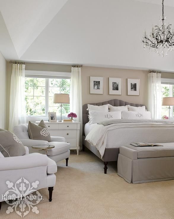 Chic bedroom features a sand colored accent wall lined with three black and whit...