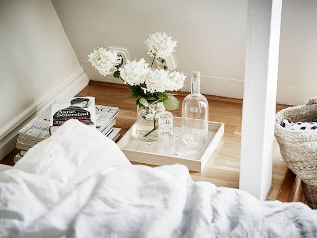 Tray and a pile of magazines as a bedside table for a low-lying bed in a calm Sw...