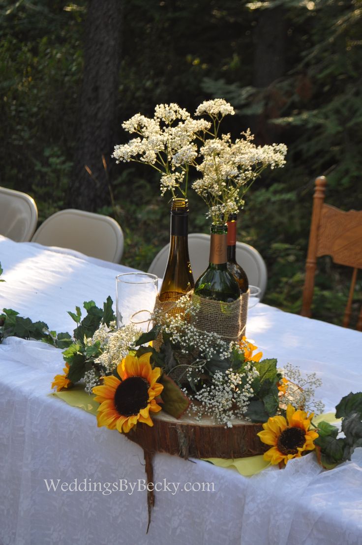 Wine bottles tied together with burlap- babies breath and sunflowers accent the ...