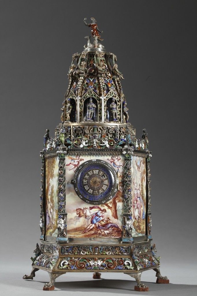Table clock in multicolored enamel and silver. The base is decorated with mythol...