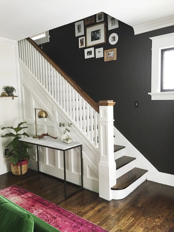 Beautiful entryway and staircase makeover with dark wall and white stairs and wo...