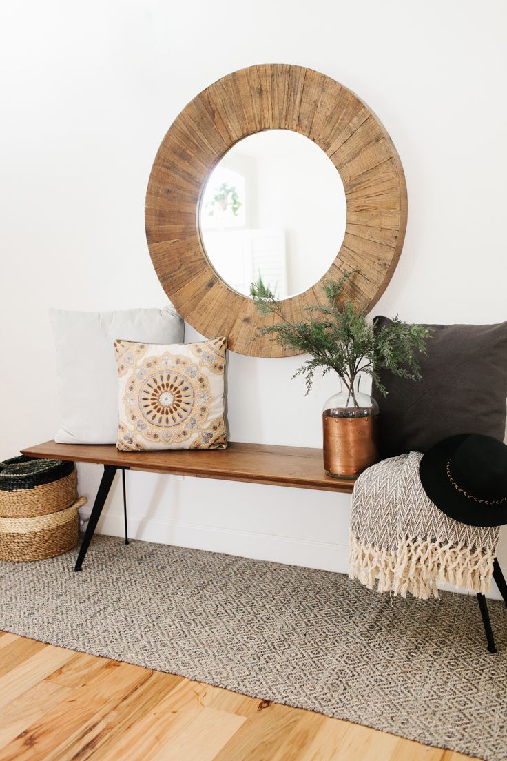 oversize round wood mirror with a midcentury modern style bench and cozy pillows...