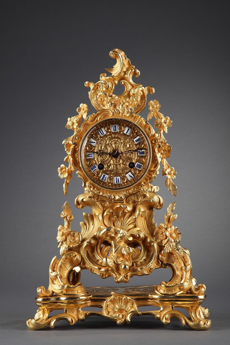 A small mantel clock in French rocaille style decorated with a rich gilt and chi...