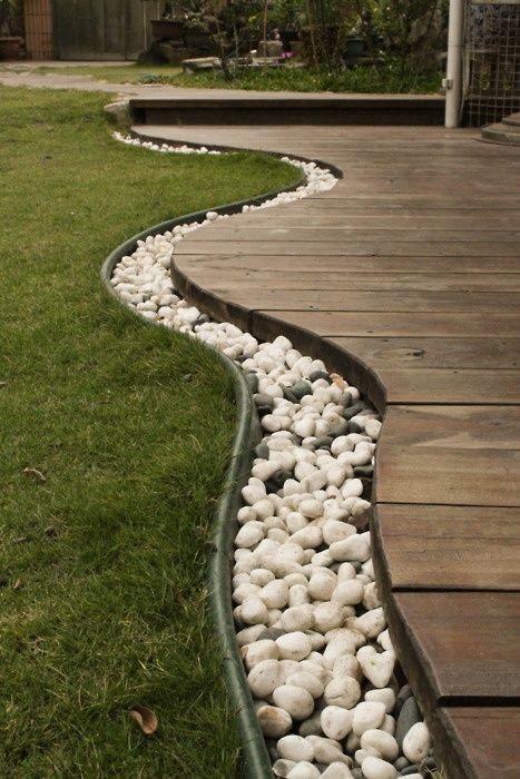 Use rocks to separate the grass from the deck, then bury rope lights in the rock...