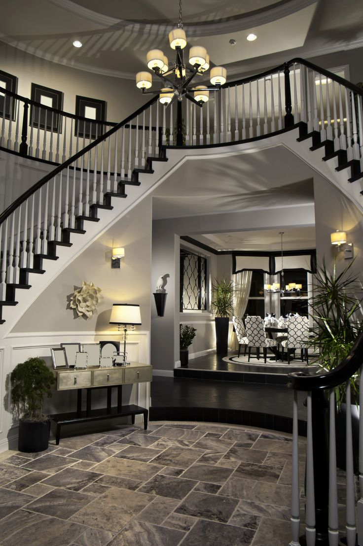 Double arched stairs descending down the round foyer creating a two-story entran...