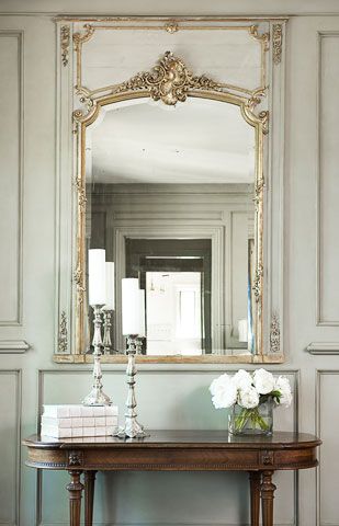 An antique mirror from France is set into the custom paneling of the master bedr...