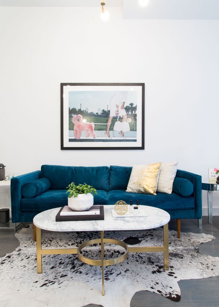 Space with a blue velvet sofa, cowhide rug, and a marble coffee table