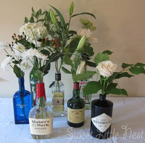 Centerpieces made from liquor bottles and simple flowers. Or wine bottles. Or ge...
