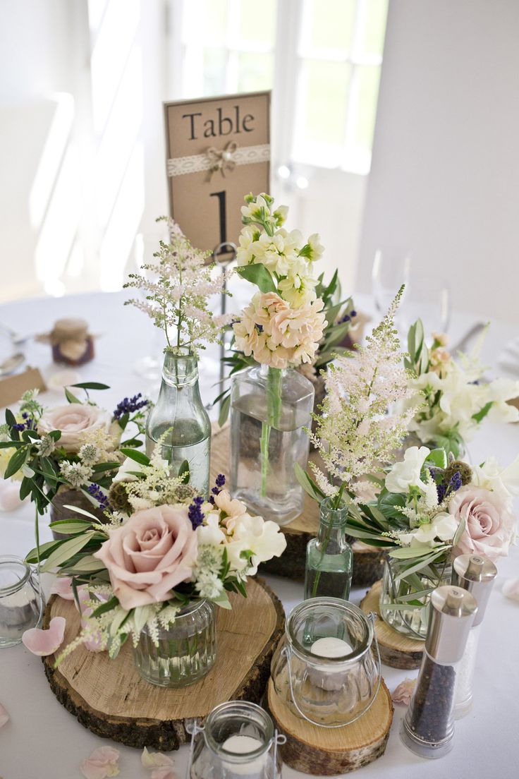 Centrepiece of Rustic Tree Slices with Jars of pink Flower Stems | Eden at Broug...