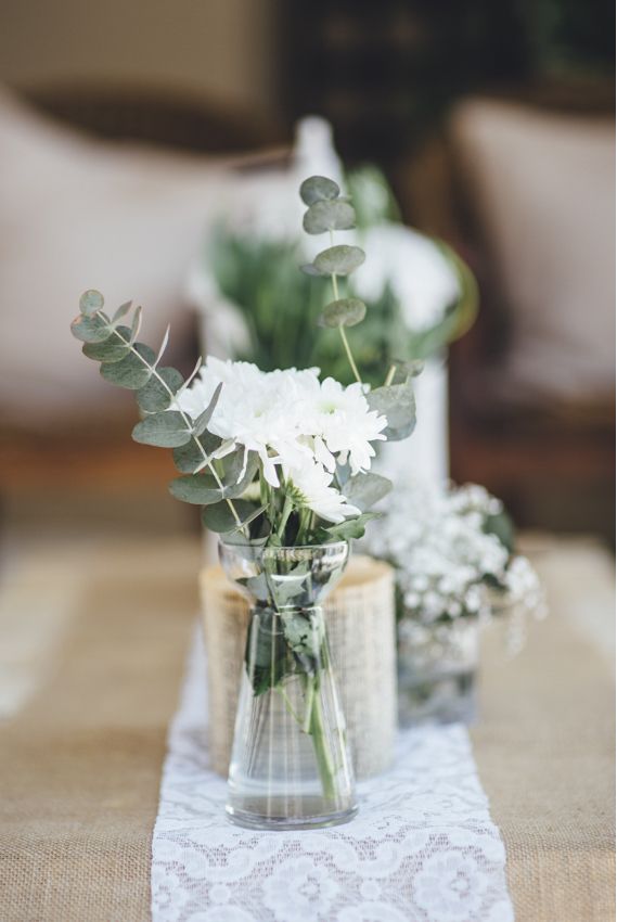 Simple rustic arrangement of chrysanthemums and eucalyptus in glass vases and bo...