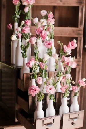 white bottle vases filled with pink flowers in an antique library card cabinet |...