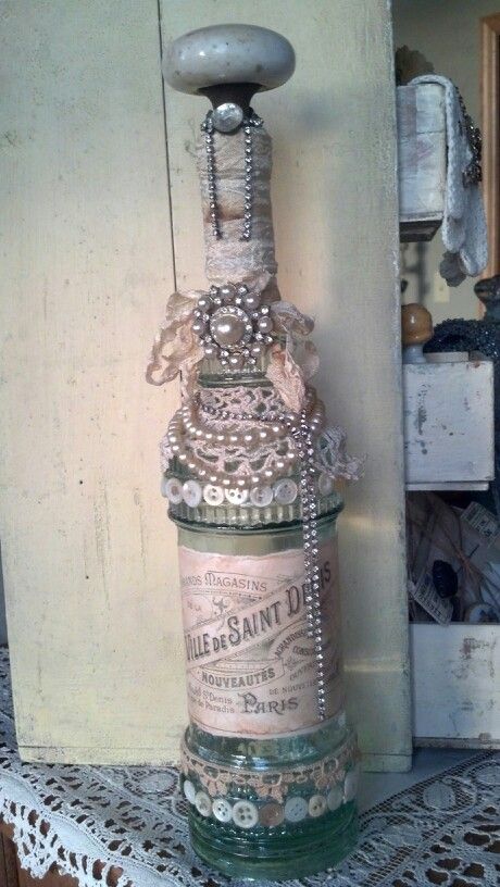 Altered bottle with lace, seam binding,  door knob, flea market jewelry.