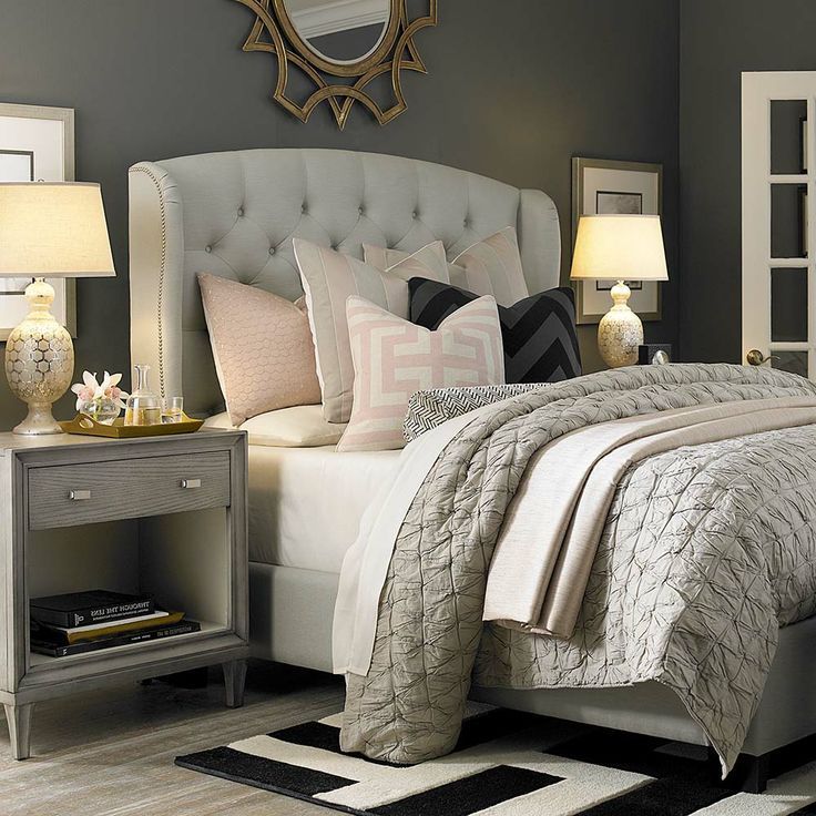 Cozy bedroom with tufted upholstered bed, neutral light grey linens w/ soft pink...