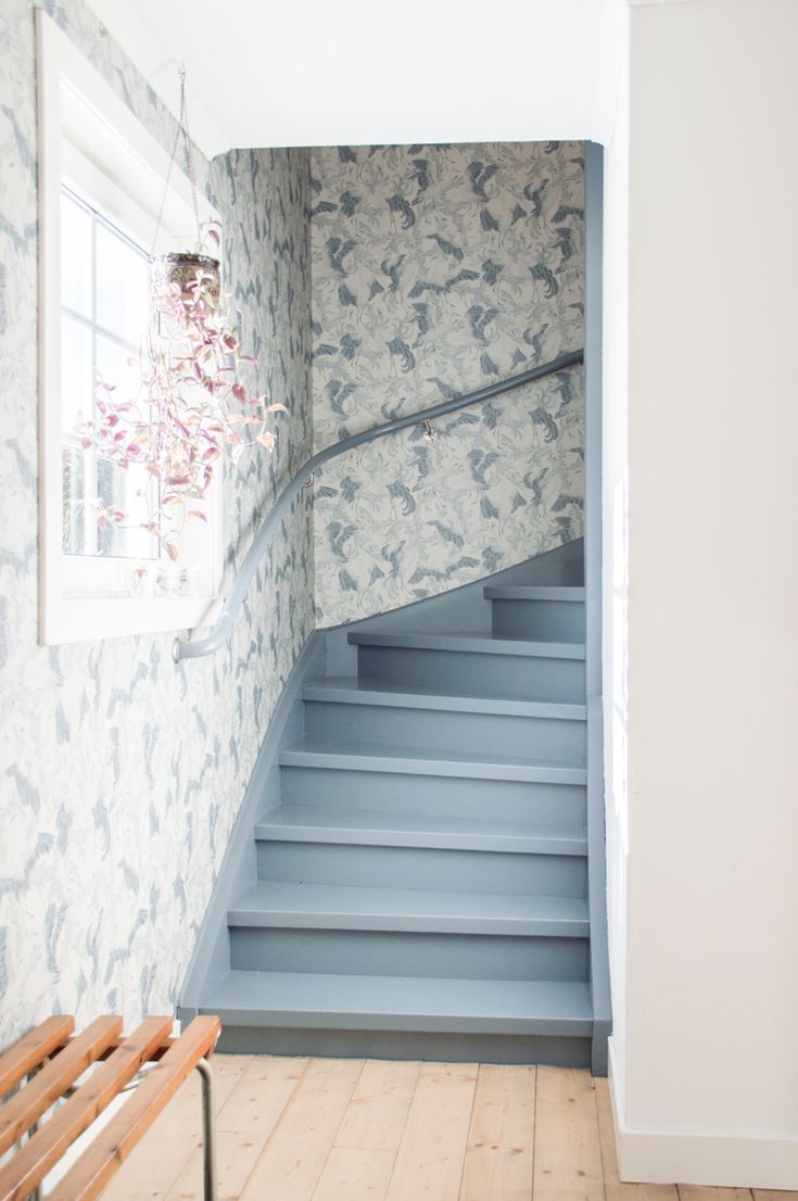 Stairs painted blue with blue and white wallpaper in a swedish house.