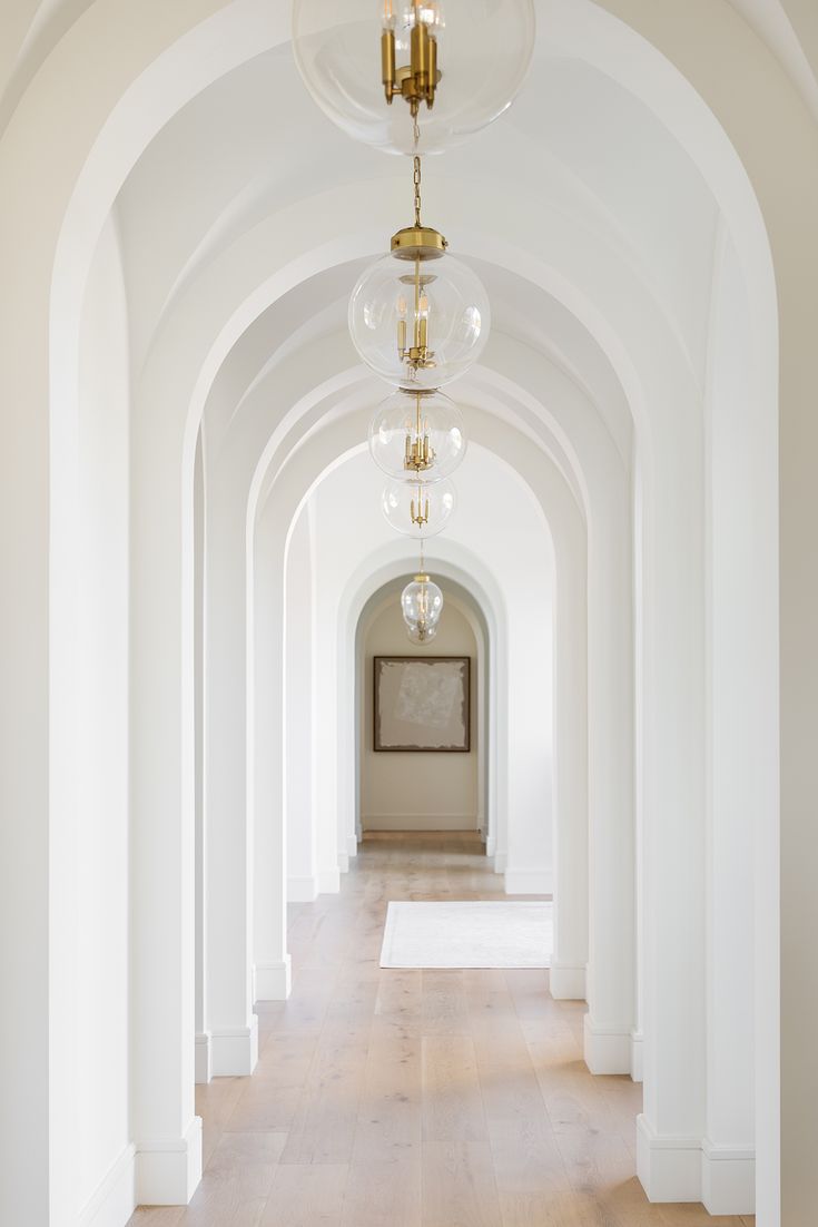 White hallway with brass pendant lamps
