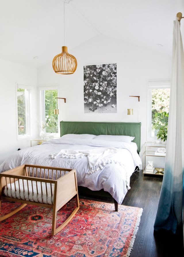 Colorful midcentury modern bedroom with a pink rug, green headboard and brass wa...