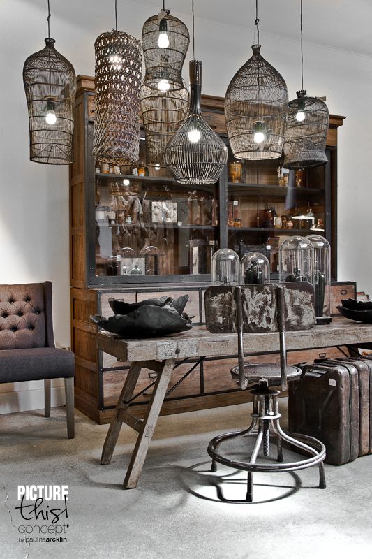 Collection of basket style lighting hanging over a rustic table and dresser