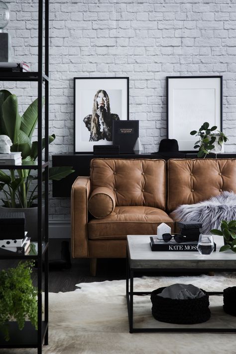 modern interior with white brick walls black elements and a tan leather sofa - l...