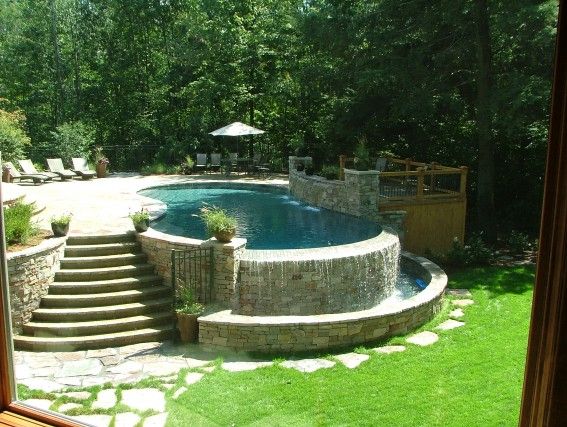 The infinity edge of this pool spills over a natural stone wall, creating a beau...