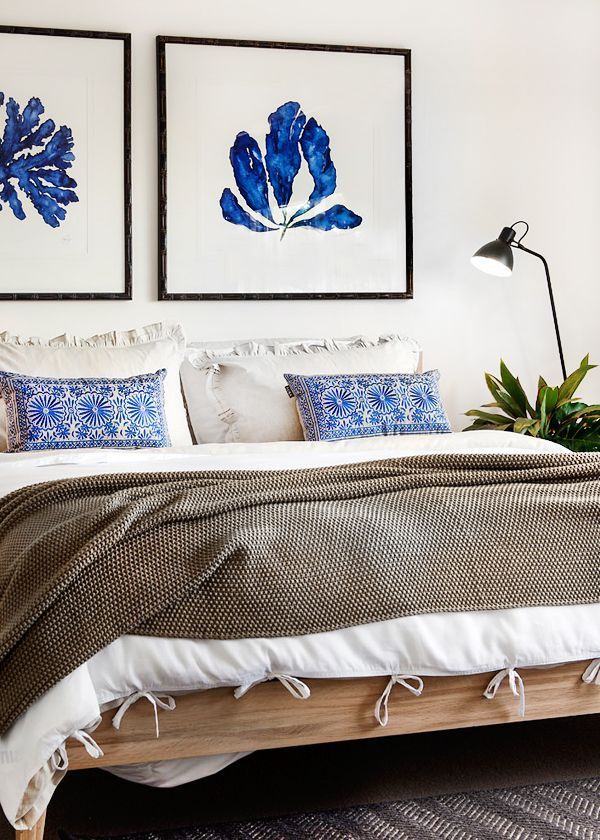 Neutral bedroom with a pop of blue in the art and pillows